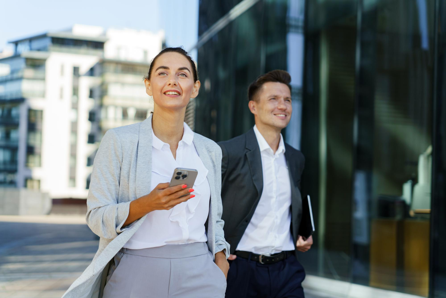 Two confident professionals walking together in a modern business district
