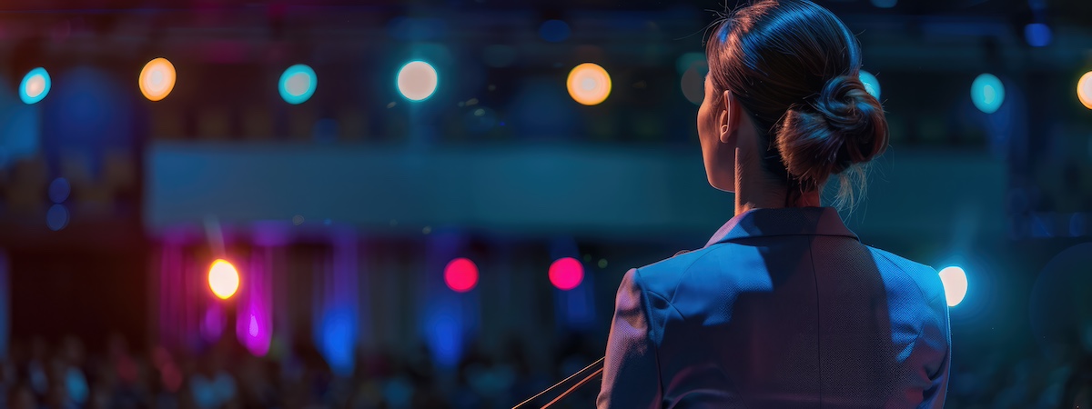 A speaker stepping onto a brightly lit conference stage