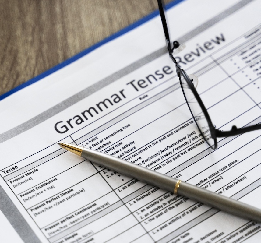 Grammar tense review sheet with pen and glasses — detailed exam preparation